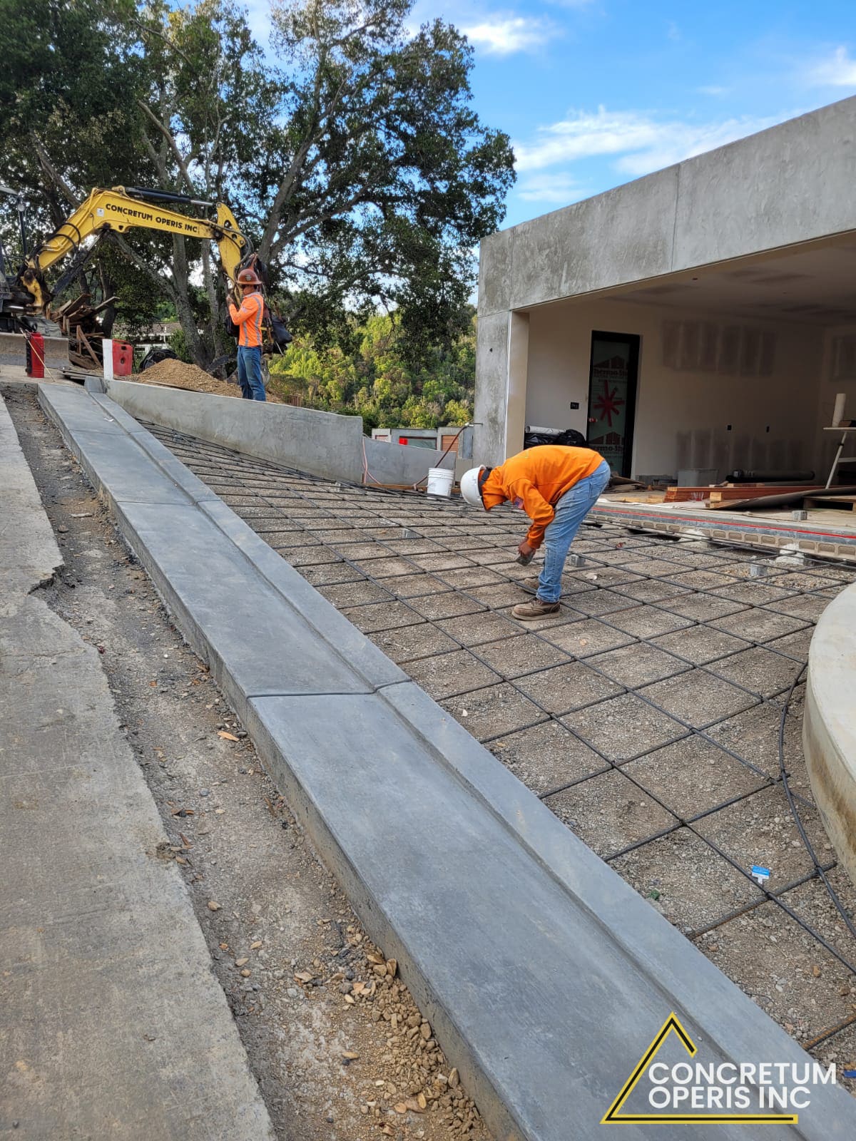 Worker placing a rebar grid for a new concrete slab near a hillside garage in San Rafael, CA