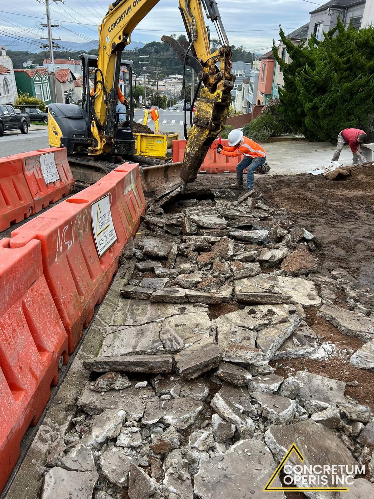 Excavator with a hydraulic hammer demolishing an old concrete sidewalk in San Francisco, CA