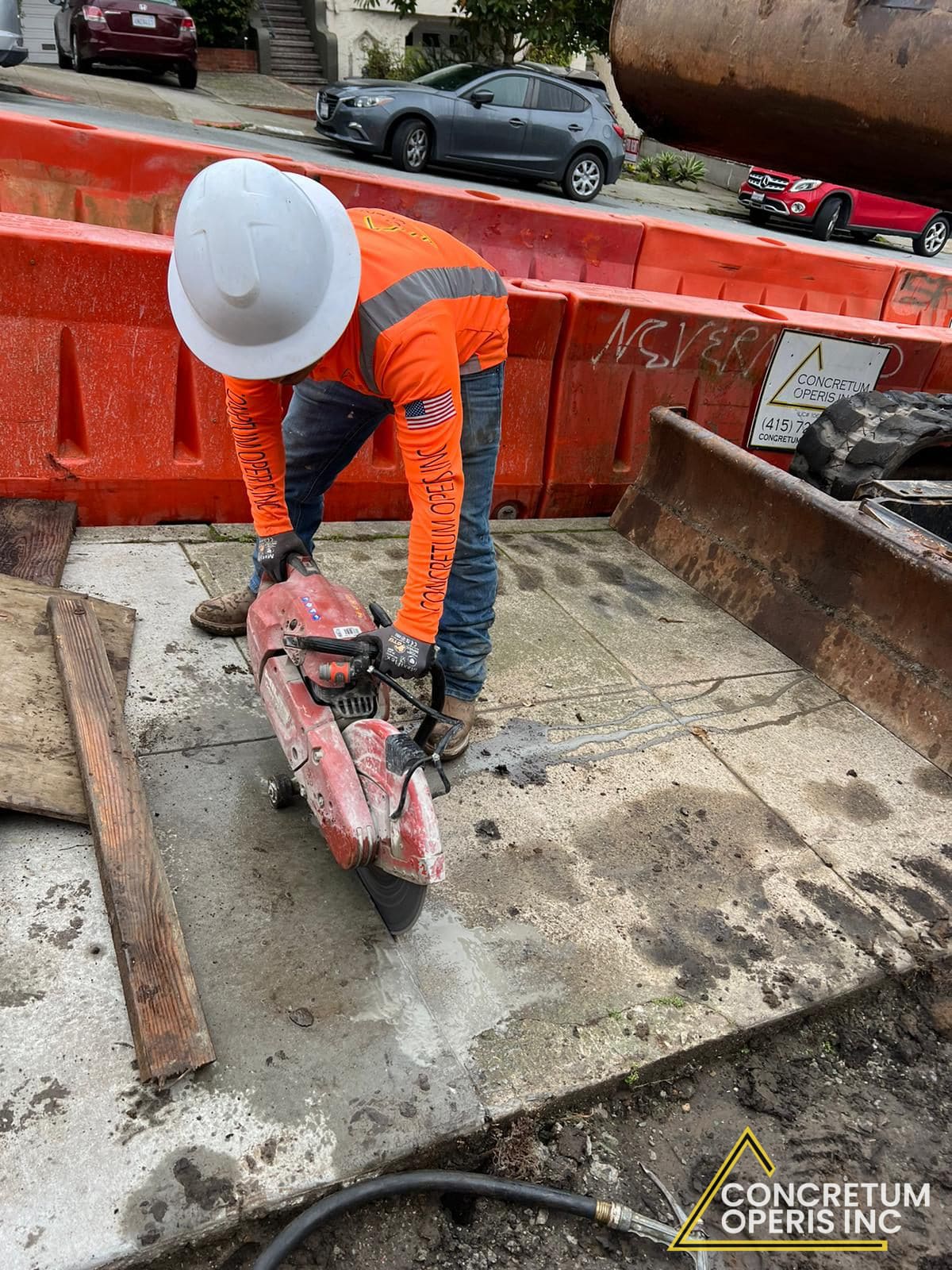 Worker cutting a concrete slab with a gas-powered saw at a San Francisco sidewalk jobsite