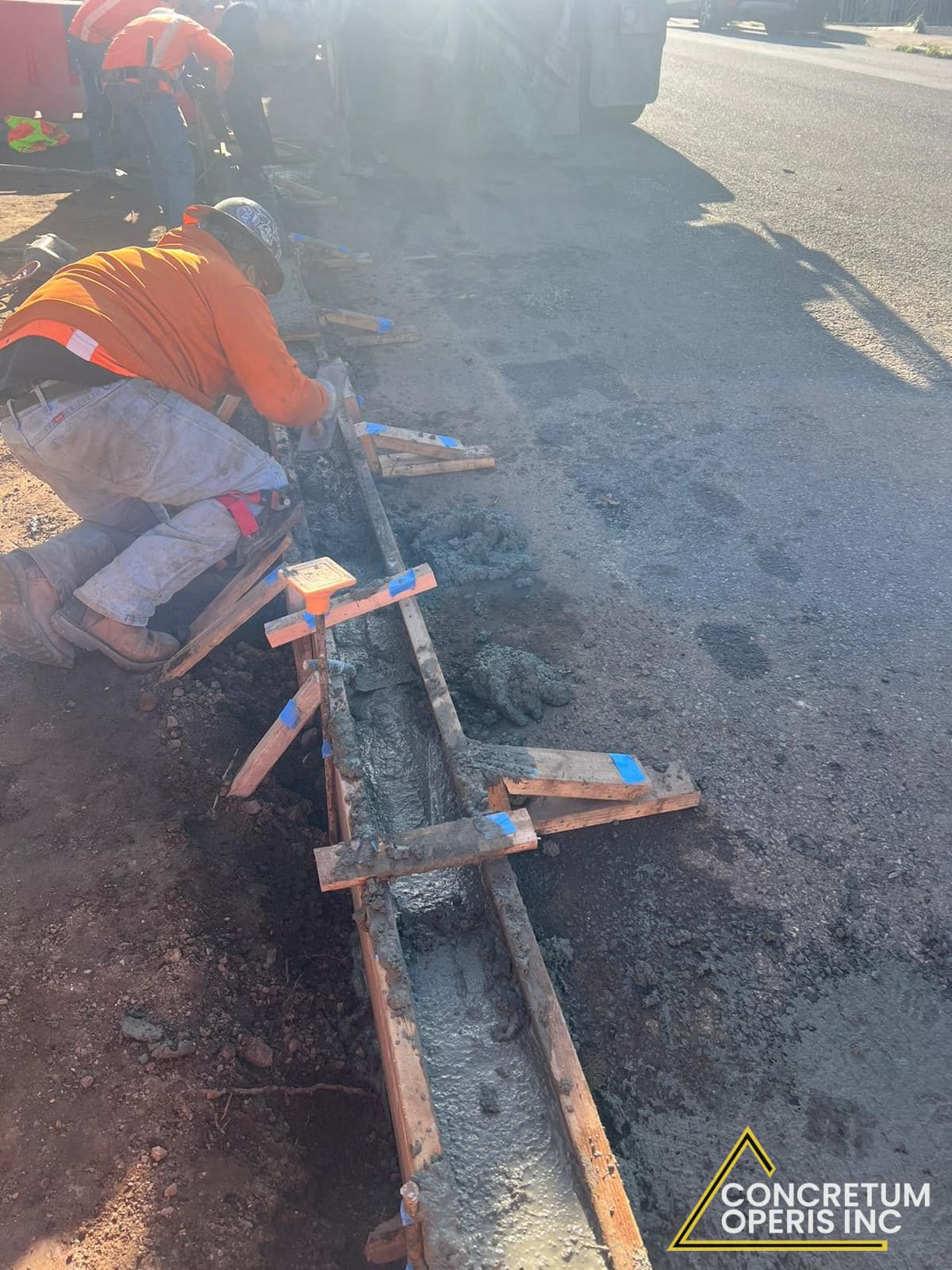 Worker finishing a freshly poured concrete curb form along a San Francisco street