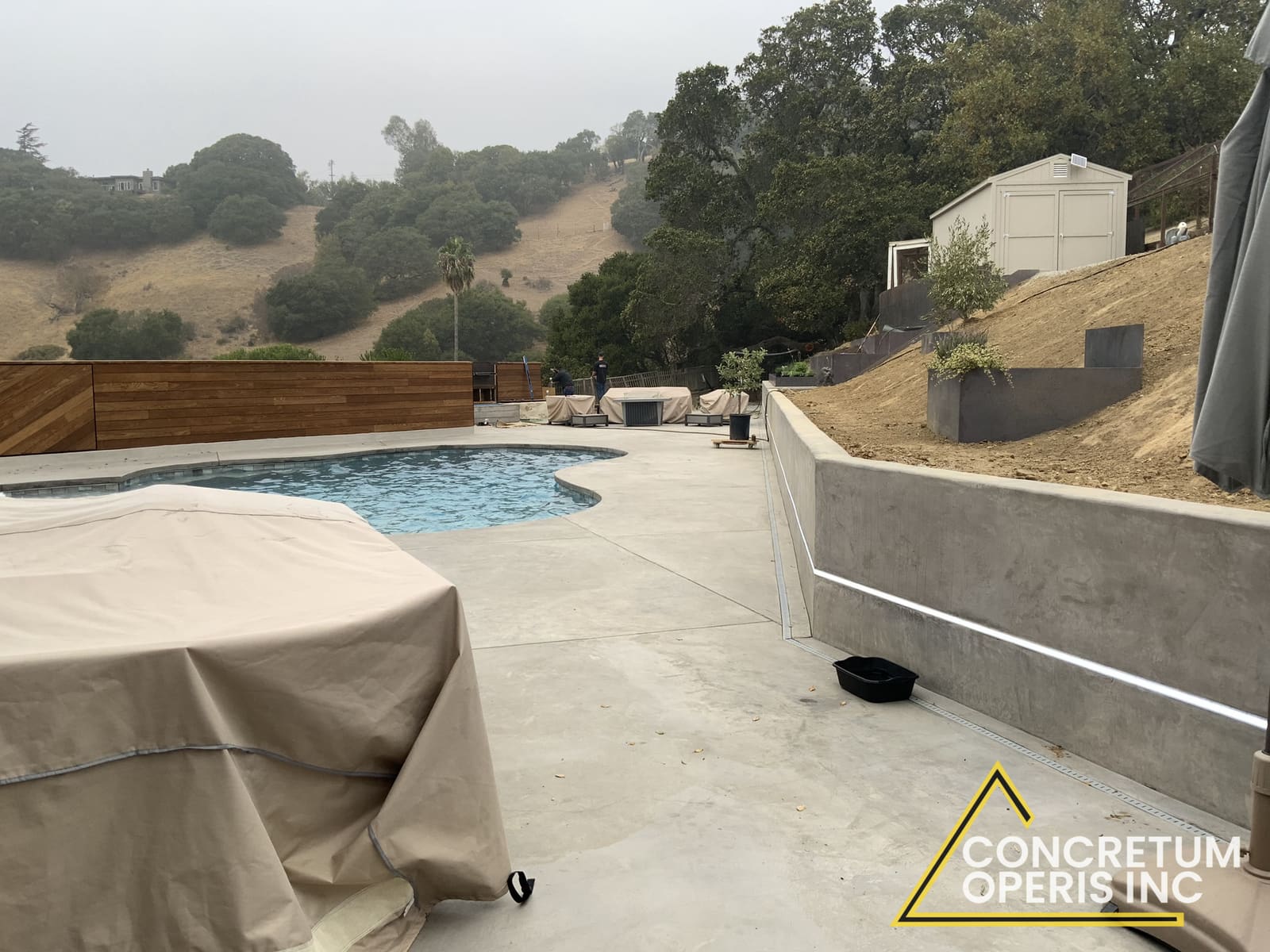 Concrete pool deck poured next to a low retaining wall overlooking Richmond, CA hills