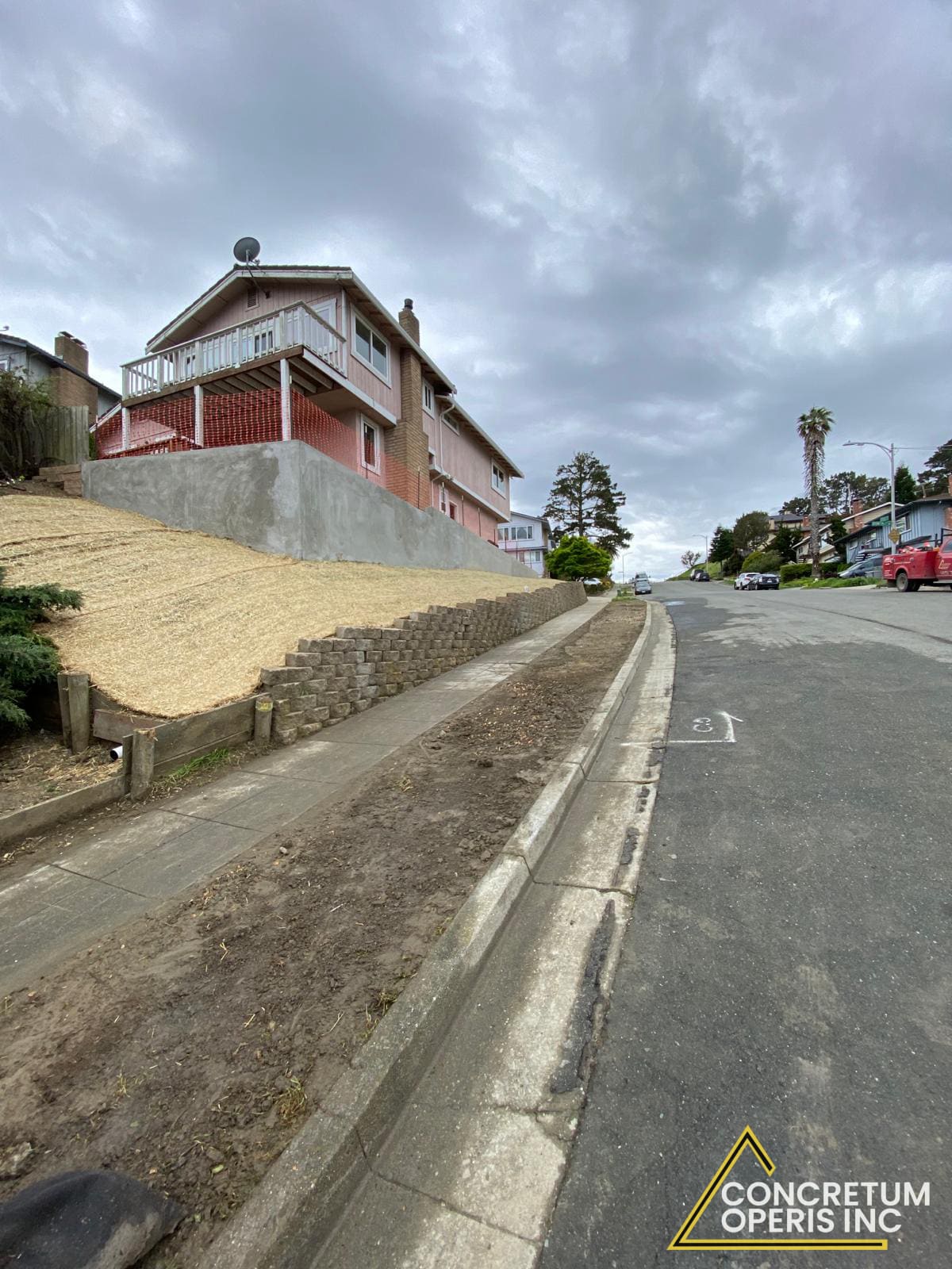 Completed concrete retaining wall along a hillside street in Bonita, CA