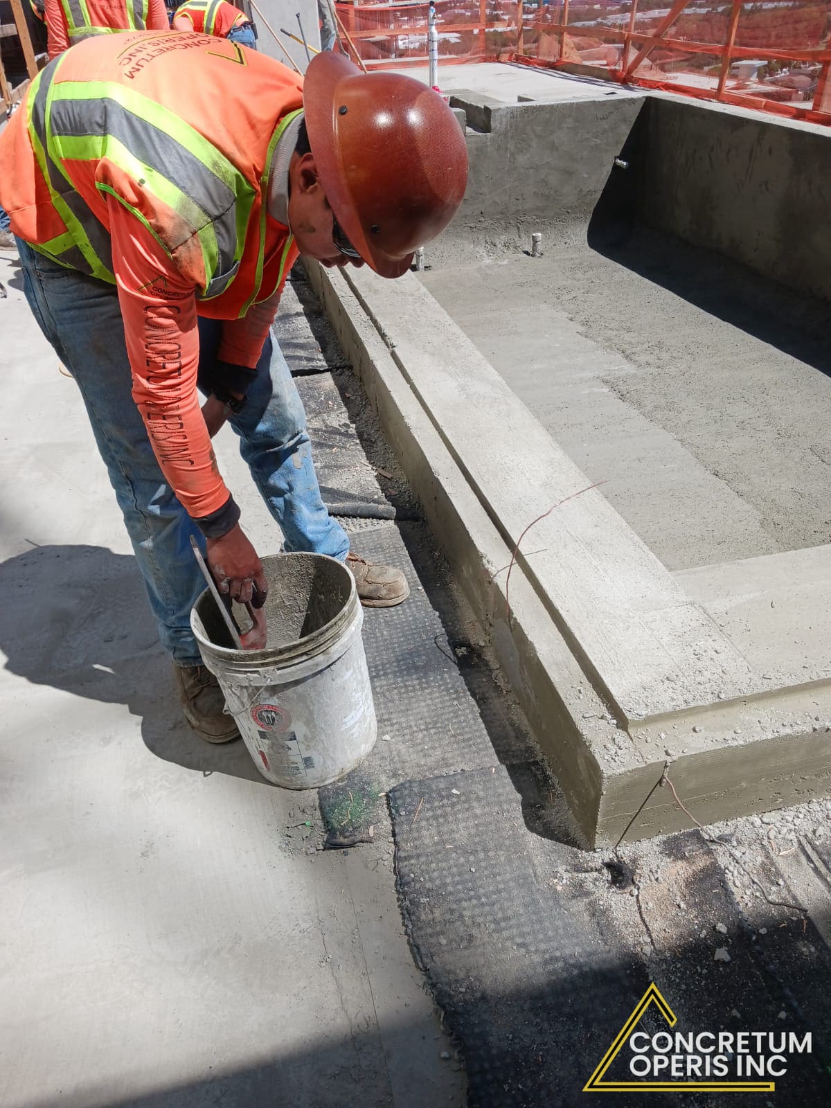 Worker hand-troweling a freshly poured concrete rooftop terrace edge in Santa Clara, CA