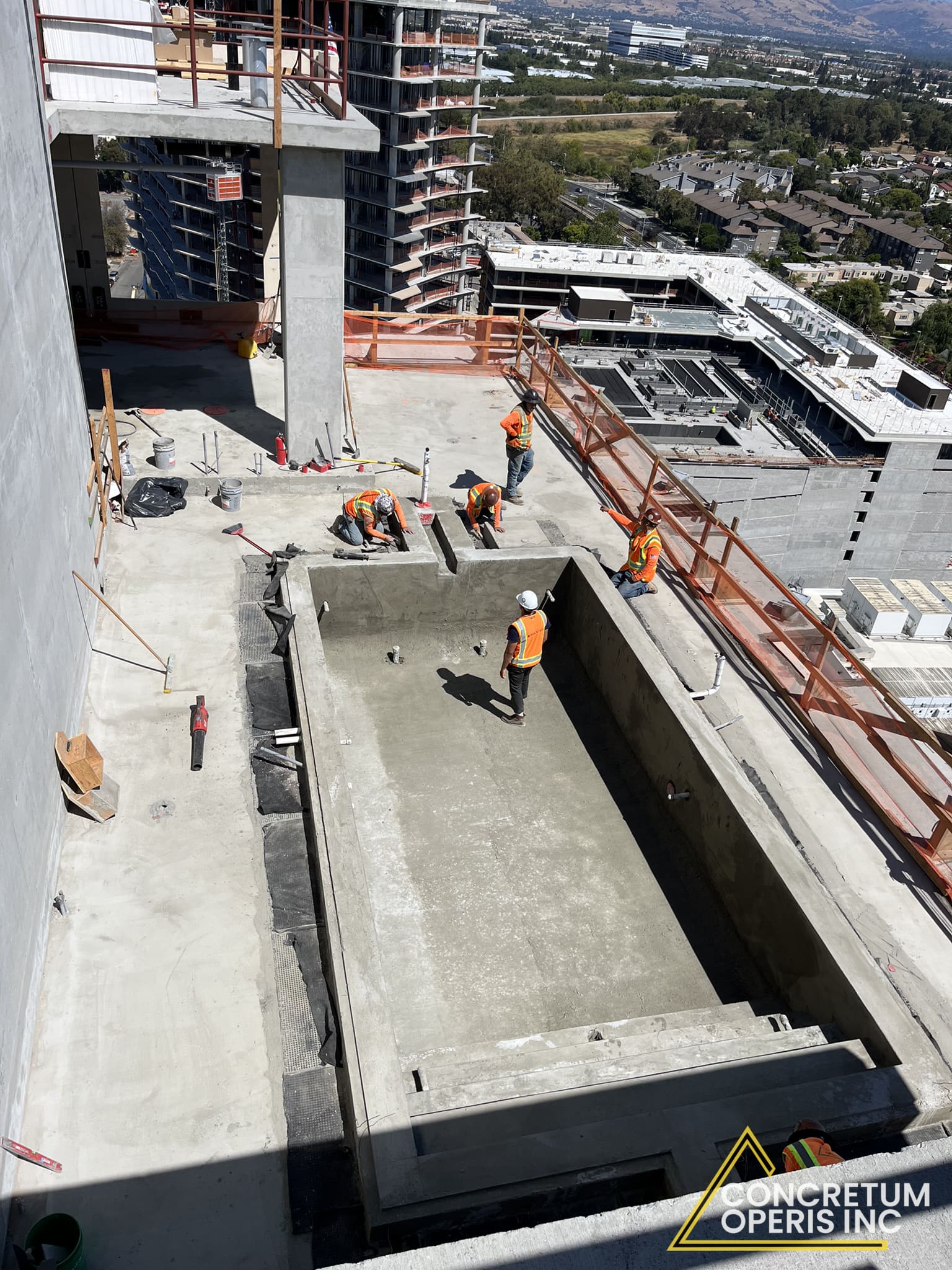 Freshly formed concrete rooftop pool and terrace overlooking Santa Clara, CA from a high-rise