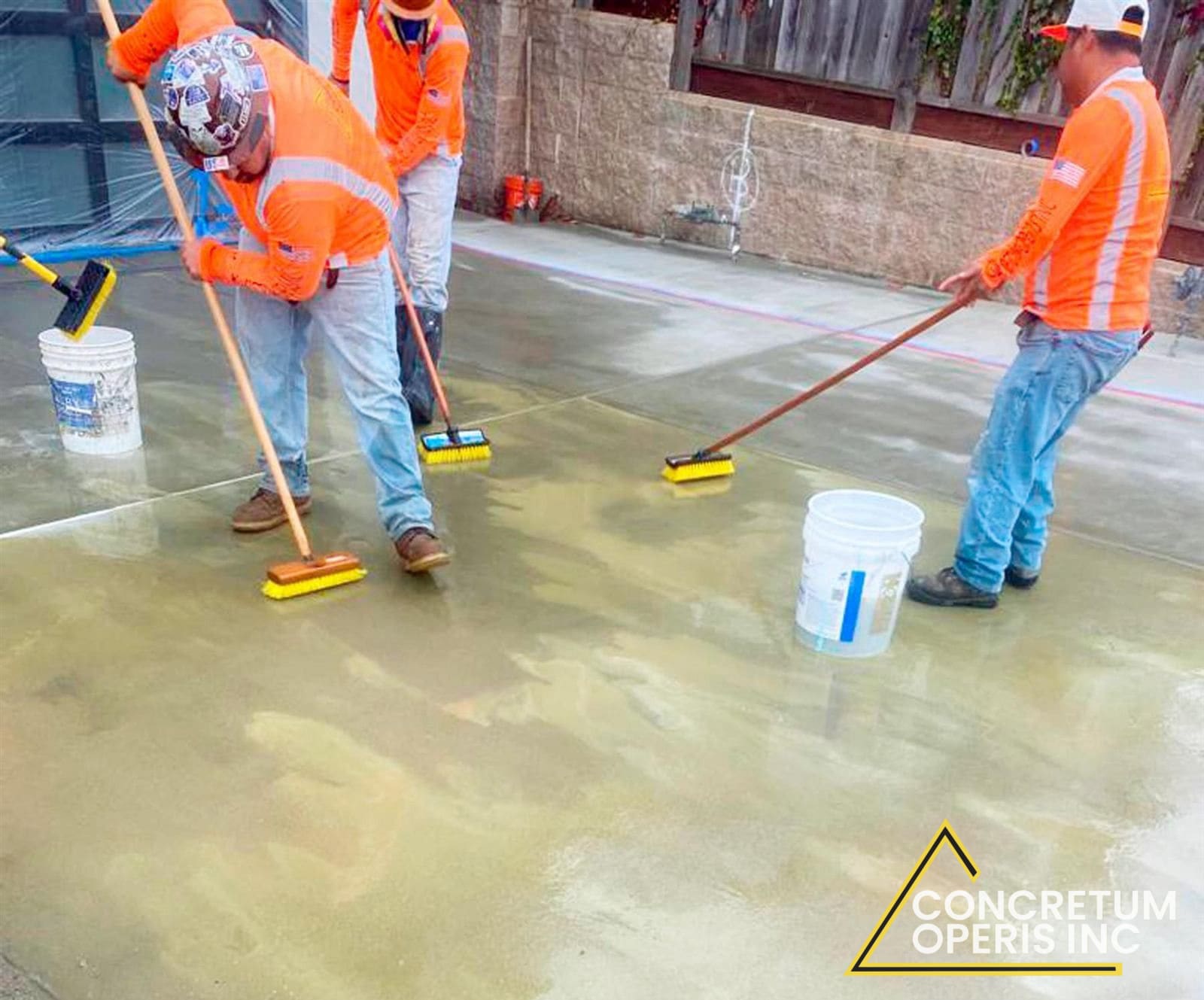 Workers broom-finishing a freshly poured concrete patio slab in Richmond, CA
