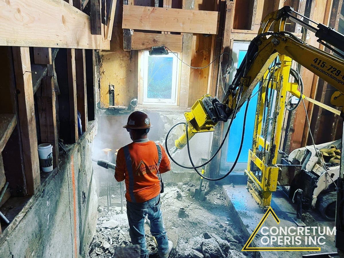 Worker operating a hydraulic breaker inside a home during interior demolition in Richmond, CA