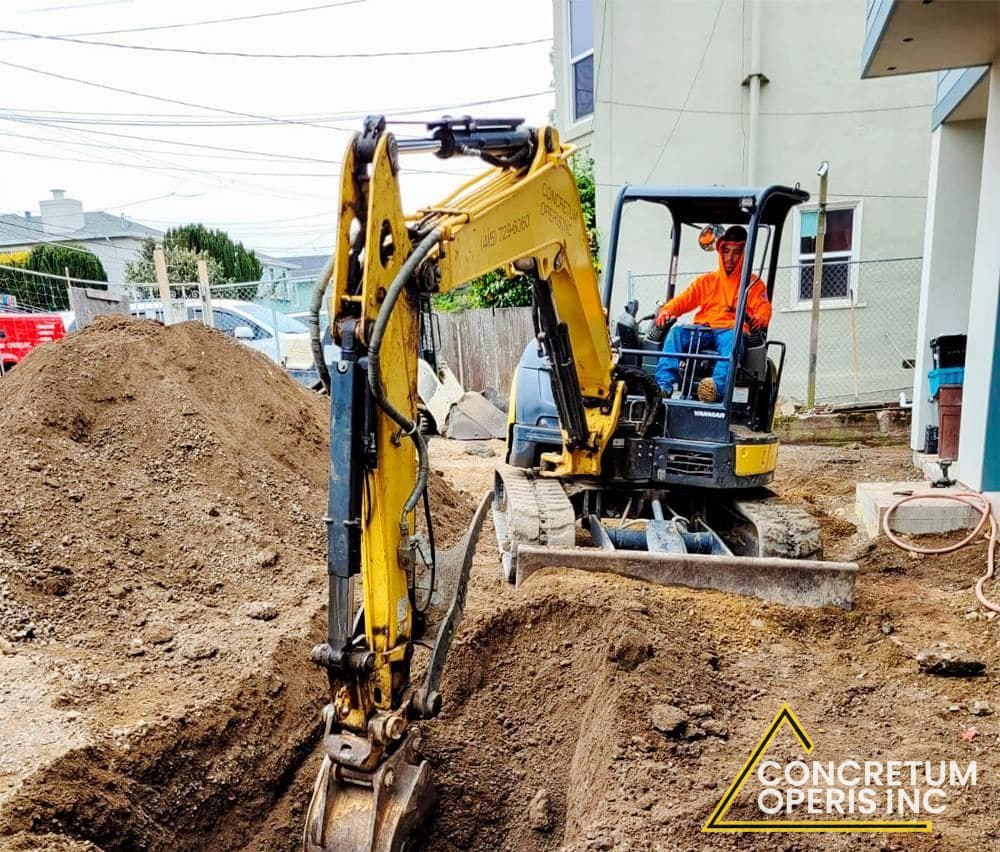 Mini excavator digging a foundation trench in a residential backyard in Richmond, CA