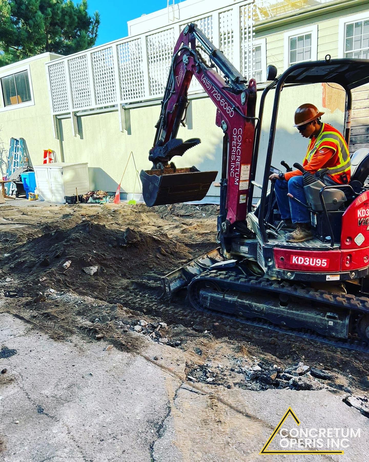 Mini excavator digging next to a building foundation in Richmond, CA