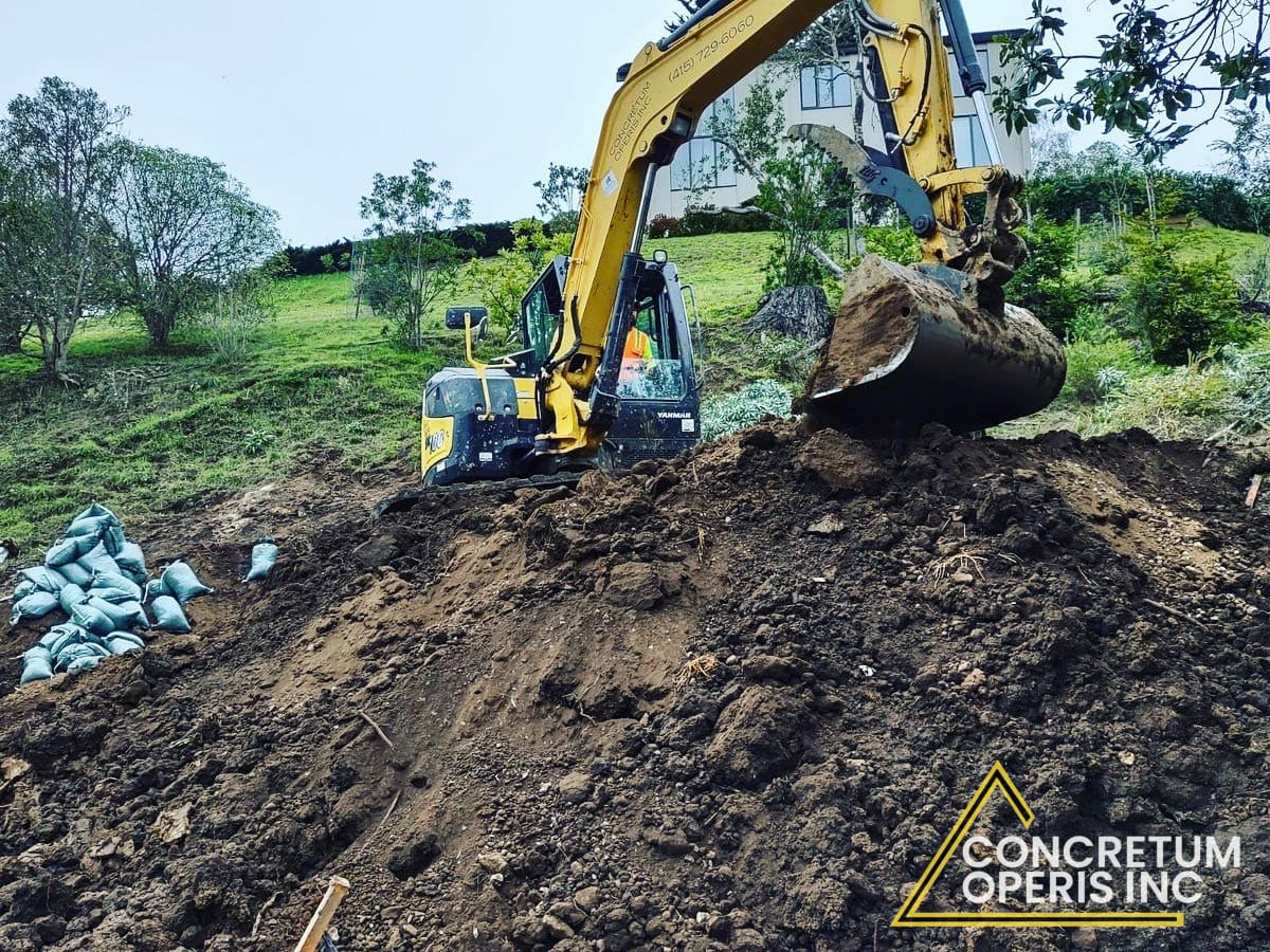 Mini excavator grading a slope on a hillside lot in Richmond, CA