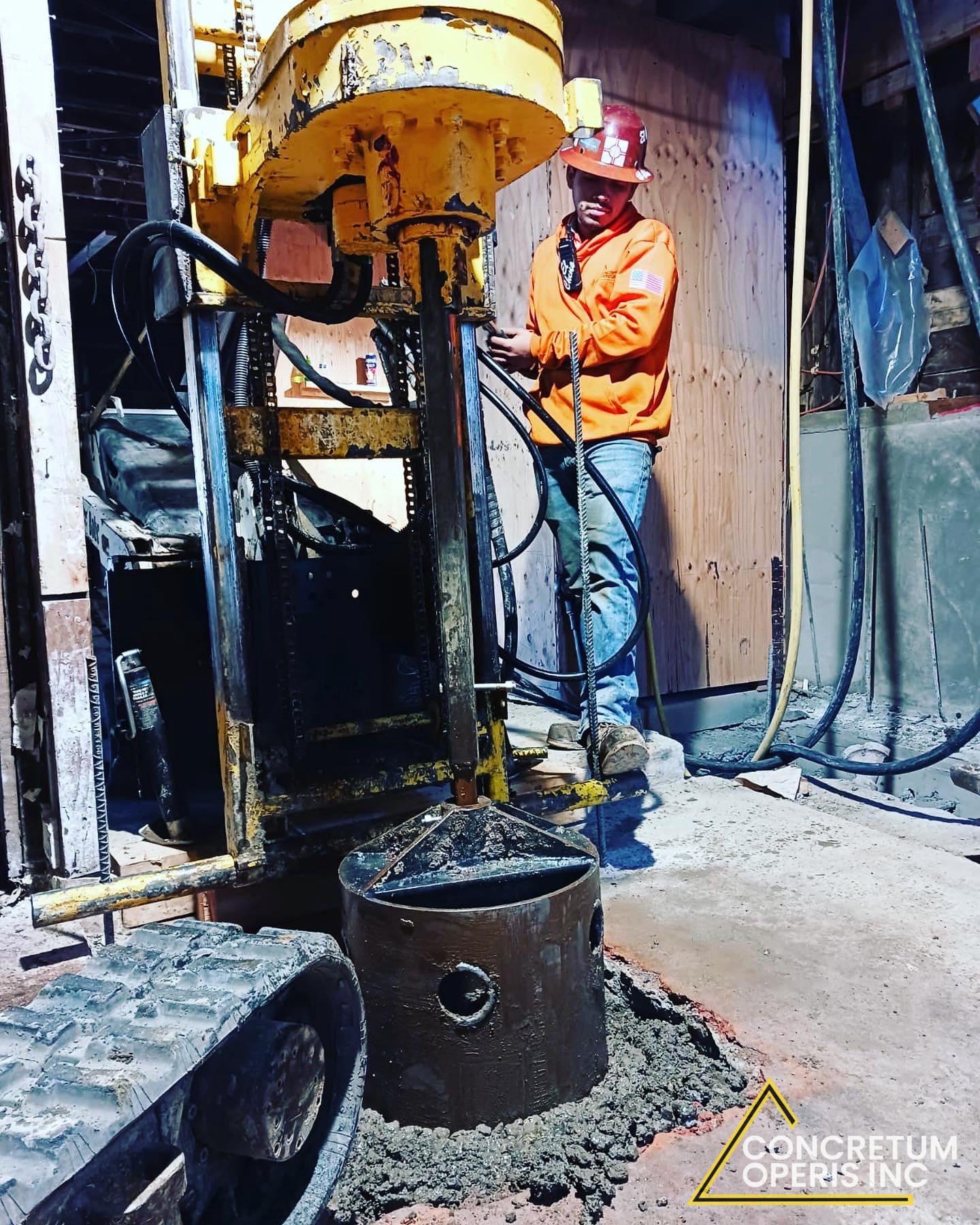 Worker operating a portable drill rig inside a home under construction in Richmond, CA