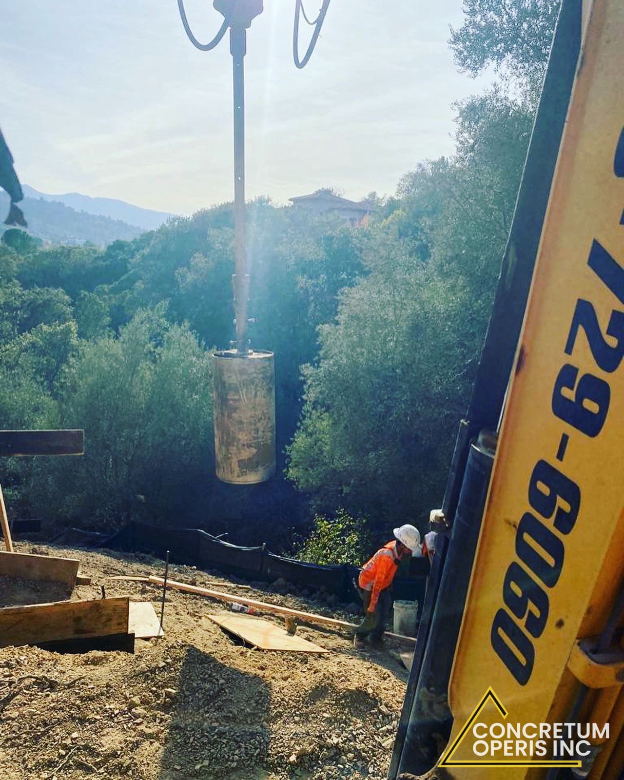 Portable drill rig boring a pier hole on a wooded hillside lot in Richmond, CA