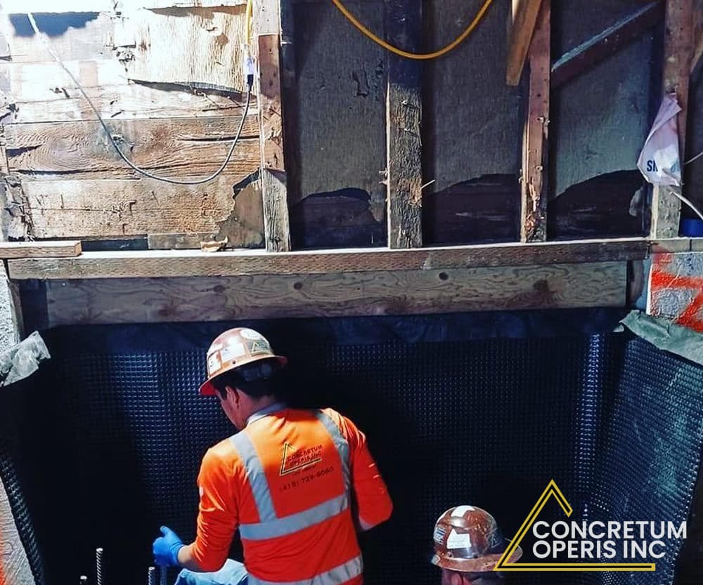 Crew entering a membrane-lined excavation beneath a home's foundation in Richmond, CA
